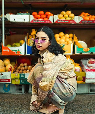 girl with glasses in front of fruit stand