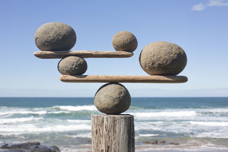 rocks-balancing-on-driftwood--sea-in-background